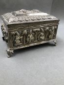 AN EASTERN SILVER HINGED BOX ON FOUR RAISED FOLIATE LEGS, THE BOX DECORATED WITH