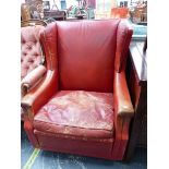 A RED LEATHER WING ARMCHAIR BY HOWARD KEITH, LABEL ON BASE.