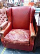 A RED LEATHER WING ARMCHAIR BY HOWARD KEITH, LABEL ON BASE.