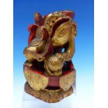 A CHINESE CARVED WOOD LION SEATED WITH A BROCADE BALL PARCEL GILT ON A RED LACQUER GROUND. H 23cms.