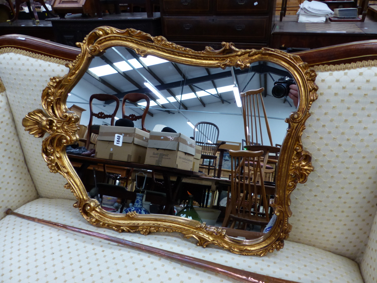 A WALL MIRROR IN A SHAPED RECTANGULAR GILT FRAME CARVED WITH FOLIAGE BRACKETS. 83 x 57cms.