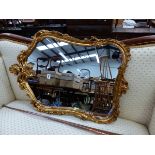 A WALL MIRROR IN A SHAPED RECTANGULAR GILT FRAME CARVED WITH FOLIAGE BRACKETS. 83 x 57cms.