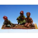 AN AUSTRIAN BERGMAN COLD PAINTED BRONZE GROUP OF THREE FEZ WEARING BOYS PLAYING DICE ON A