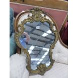 A SHAPED MIRROR IN GILT ROCOCO FRAME CRESTED BY A CABOCHON CENTRED TREFOIL. 68 x 46cms.