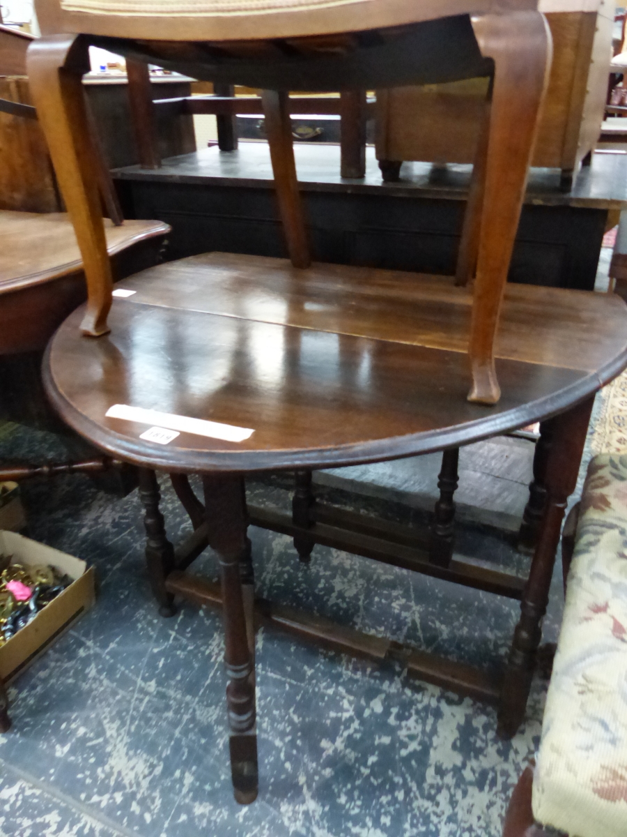 AN OAK OVAL DROP FLAP TABLE, THE GUN BARREL LEGS JOINED BY STRETCHERS ABOVE THE INVERTED CUP FEET. W