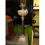 AN ANTIQUE OIL LAMP WITH ENGRAVED AND CUT GLASS RECEIVER RAISED ON A SILVER PLATED CORINTHIAN COLUMN