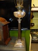 AN ANTIQUE OIL LAMP WITH ENGRAVED AND CUT GLASS RECEIVER RAISED ON A SILVER PLATED CORINTHIAN COLUMN