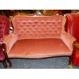 AN EDWARDIAN MAHOGANY SETTEE BUTTON BACKED IN PINK VELVET BELOW A TOP RAIL CENTRED BY AN ANTHEMION