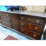 AN OAK DRESSER BASE WITH THE CENTRAL DOOR FLANKED BY BANKS OF THREE DRAWERS OVER BRACKET FEET. W 182