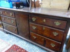 AN OAK DRESSER BASE WITH THE CENTRAL DOOR FLANKED BY BANKS OF THREE DRAWERS OVER BRACKET FEET. W 182