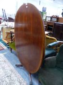 A CROSS BANDED MAHOGANY OVAL TILT TOPPED TABLE ON A BALUSTER COLUMNAND TRIPOD WITH BRASS PAW