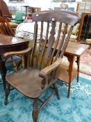 AN OAK KITCHEN ELBOW CHAIR WITH SHAPED PLATE FLANKED BY TWO BARS, THE SADDLE SEAT ON BALUSTER