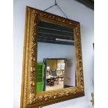 A 19TH CENTURY RECTANGULAR MIRROR IN A GILT FRAME WITH A RAISED FRUIT AND FLOWER BAND. 144 x 110cms.