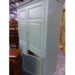 A 19th C. PINE GREEN PAINTED CUPBOARD WITH TWO PAIRS OF PANELLED DOORS ABOVE AND BELOW A BRUSHING SL