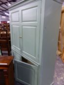 A 19th C. PINE GREEN PAINTED CUPBOARD WITH TWO PAIRS OF PANELLED DOORS ABOVE AND BELOW A BRUSHING SL