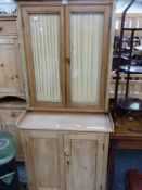 A PINE SIDE CABINET, THE TOP WITH GLAZED DOORS OVER SHELVES RECESSED ABOVE TWO PANELLED DOORS. W