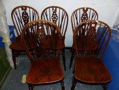 A SET OF FIVE OAK SADDLE SEATED WHEEL BACKED CHAIRS ON TURNED LEGS