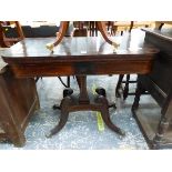 A REGENCY LINE INLAID MAHOGANY GAMES TABLE THE SWIVEL TOP ON A WAISTED SQUARE COLUMN, THE FOUR LEGS