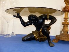 A SMOKEY GLASS OVAL TOPPED TABLE SUPPORTED BY A NUBIAN FIGURE ON ON KNEE. W99 x D 63 x H 52cms.