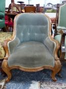 A VICTORIAN WALNUT HOOP BACK SHOW FRAME ARMCHAIR BUTTON UPHOLSTERED IN GREY VELVET, THE KNEES OF THE