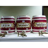 THREE POTTERY SPIRIT BARRELS, EACH WITH BRASS SPIGOTS AND CLARET BANDING ABOUT GILT LABELS,