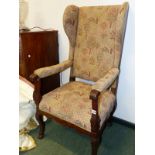 AN ANTIQUE CONTINENTAL OAK WING ARMCHAIR, THE PADDED ARMS WITH FLUTE CARVED HANDLES, THE LEGS CARVED