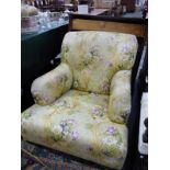 A DEEP SEATED UPHOLSTERED ARMCHAIR ON SQUARE LEGS TAPERING TO BRASS CASTERS IN THE MANNER OF HOWARD