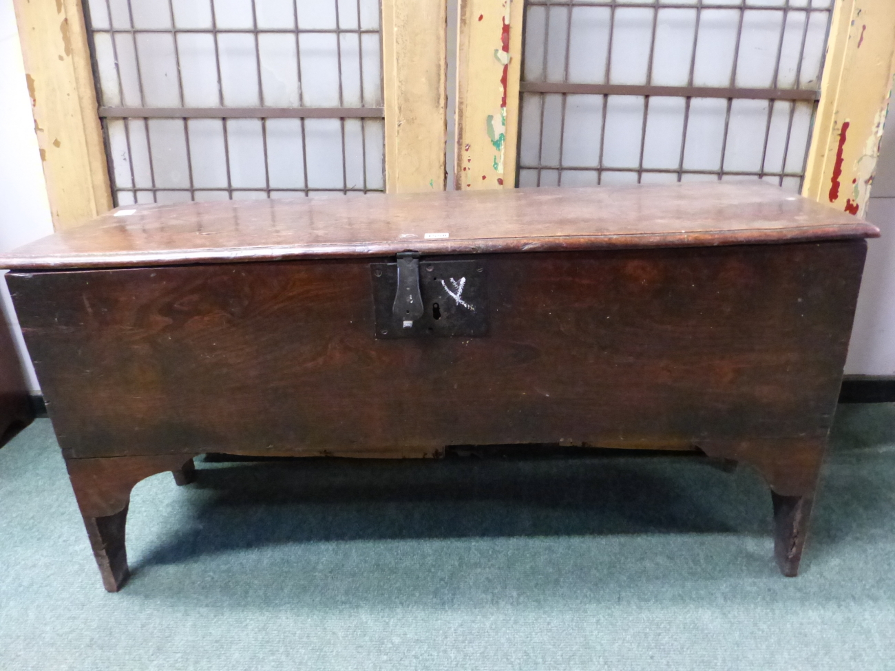 AN EARLY 18th C. OAK PLANK SIDED COFFER, THE NARROW SIDES CARVED WITH AN ARCH TO FORM THE LEGS AND