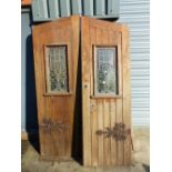 A PAIR OF GOTHIC OAK DOORS WITH FAUX STRAP HINGES AND STAINED GLASS PANELS COMPLETE WITH SURROUND.