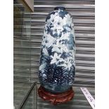 AN ORIENTAL PORCELAIN VASE PAINTED WITH LILIES. H 57cms. ON A WOOD STAND