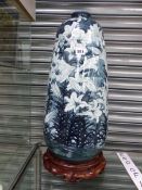AN ORIENTAL PORCELAIN VASE PAINTED WITH LILIES. H 57cms. ON A WOOD STAND