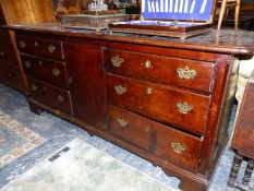 AN OAK DRESSER BASE WITH THE CENTRAL DOOR FLANKED BY BANKS OF THREE DRAWERS OVER BRACKET FEET. W 182