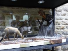 AN ART DECO SPELTER GROUP OF A LADY ON ONE KNEE FEEDING TWO DEER, THE BROWN ONYX BASE SIGNED D