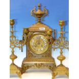 A BRASS CLOCK GARNITURE, THE TWO HANDLED CASE OF THE CLOCK SURMOUNTED BY AN URN, THE MOVEMENT