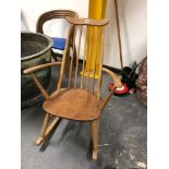 AN ERCOL ROCKING CHAIR WITH WAVY TOP RAIL, FIVE STICK BACK CURVED ARMS AND SADDLE SEAT