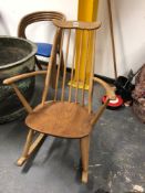 AN ERCOL ROCKING CHAIR WITH WAVY TOP RAIL, FIVE STICK BACK CURVED ARMS AND SADDLE SEAT