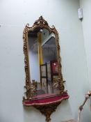 AN OGEE ARCHED GIRANDOLE WITH TWO CANDLESTICKS ABOVE A RED VELVET SHELF, THE GILT FRAME WITH FOLIAGE