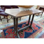 AN ARTS AND CRAFTS OAK TABLE WITH TRIANGULAR NARROW ENDS ABOVE PAIRS OF LEG JOINED ABOVE THE FEET BY
