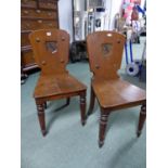 A PAIR OF 19th C. OAK HALL CHAIRS, THE BACKS WITH SHIELD SHAPED PANELS PAINTED WITH FALCON CRESTS,