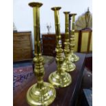 A SET OF FOUR 18th C. BRASS CANDLESTICKS, EACH TURNED WITH BUN KNOPS BELOW GUN BARREL COLUMNS ONCE