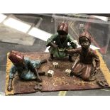 AN AUSTRIAN COLD PAINTED BRONZE GROUP OF THREE FEZ WEARING BOYS PLAYING DICE ON A GOLD TASSELLED RED