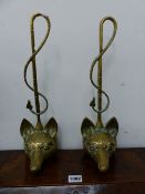 A PAIR OF BRASS FOX MASK DOOR STOPS WITH HUNTING WHIP HANDLES