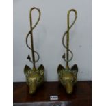 A PAIR OF BRASS FOX MASK DOOR STOPS WITH HUNTING WHIP HANDLES