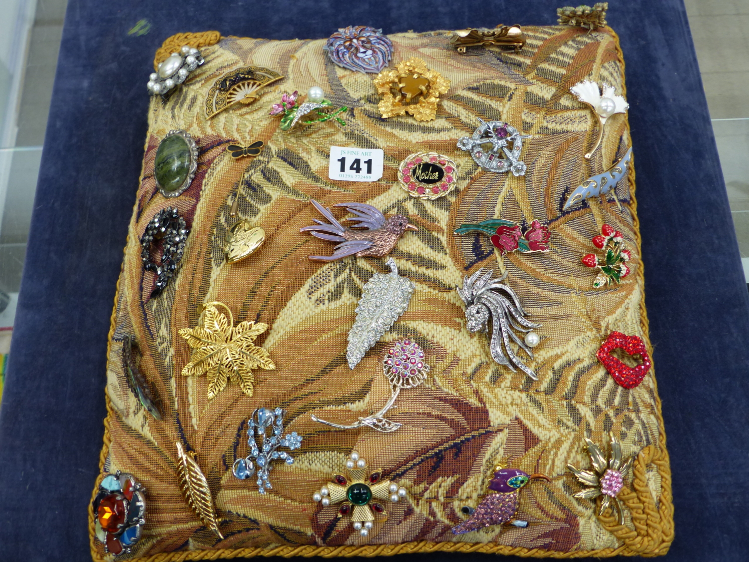 A QUANTITY COSTUME BROOCHES ON A TAPESTRY CUSHION