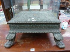 AN INDIAN BRASS LOW TABLE WITH A CENTRAL FLOWER HEAD IN RELIEF, THE LEAF ORNAMENTED CABRIOLE LEGS ON