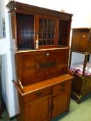 AN ARTS AND CRAFTS MAHOGANY WRITING CABINET WITH SHELVES FLANKING A GLAZED CUPBOARD ABOVE THE FALL