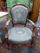 A VICTORIAN WALNUT SHOW FRAME ARMCHAIR, THE GREY GROUND FLORAL UPHOLSTERED BACK