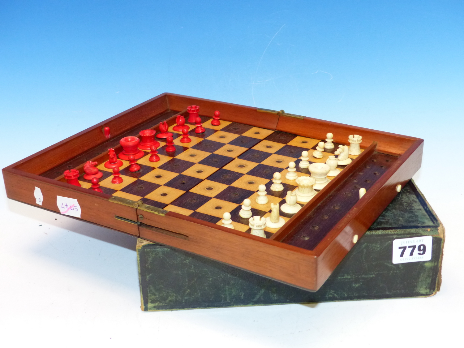 A JAQUES TRAVELLERS CHESS SET, THE MAHOGANY BOARD WITH LOCKS TO HOLD THE RED AND WHITE PIECES IN