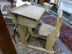 TWO OAK SCHOOL DESKS, ONE WITH THE CHAIR FIXED BEHIND THE WRITING SURFACE HINGED OVER A COMPARTMENT