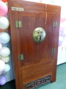 A CHINESE HARDWOOD CUPBOARD, THE DOORS CLOSING ON A CENTRAL CIRCULAR BRASS PLATE AND